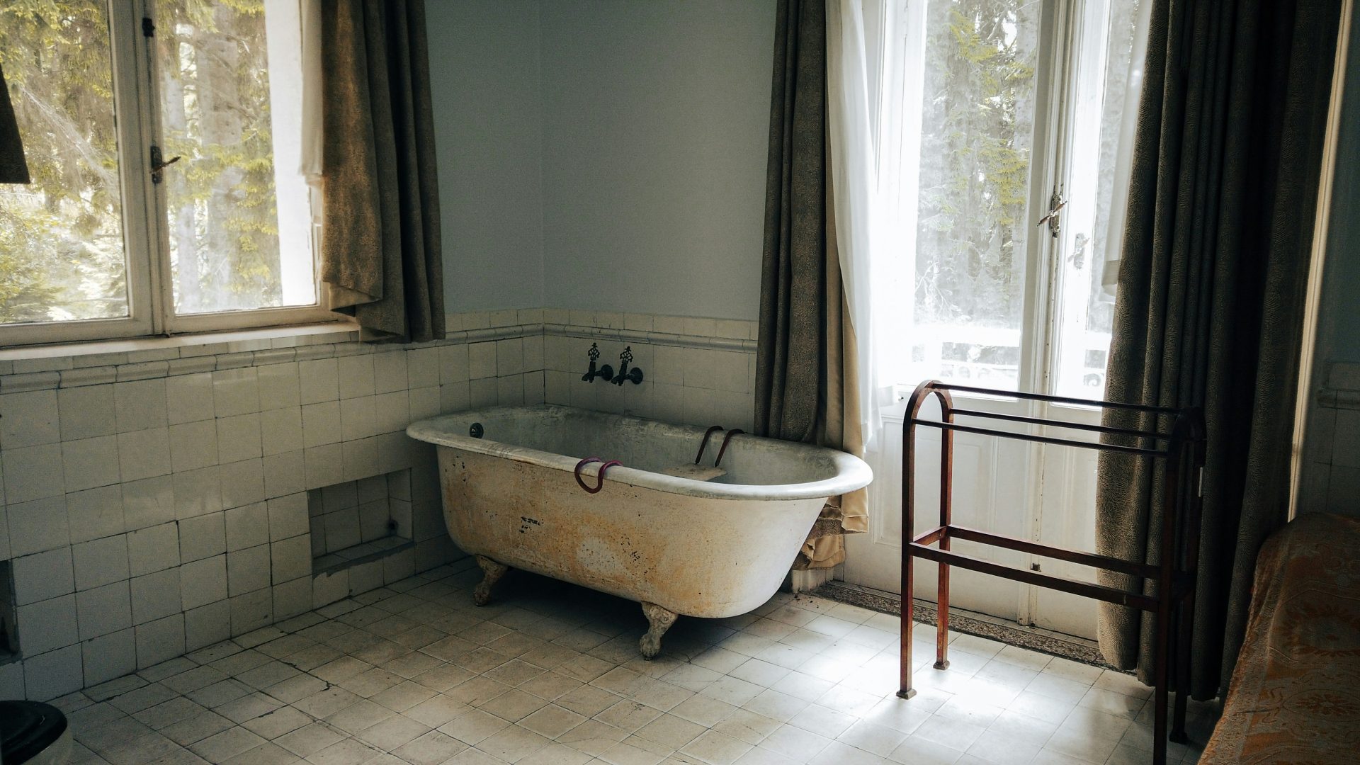 white ceramic bathtub near white window curtain